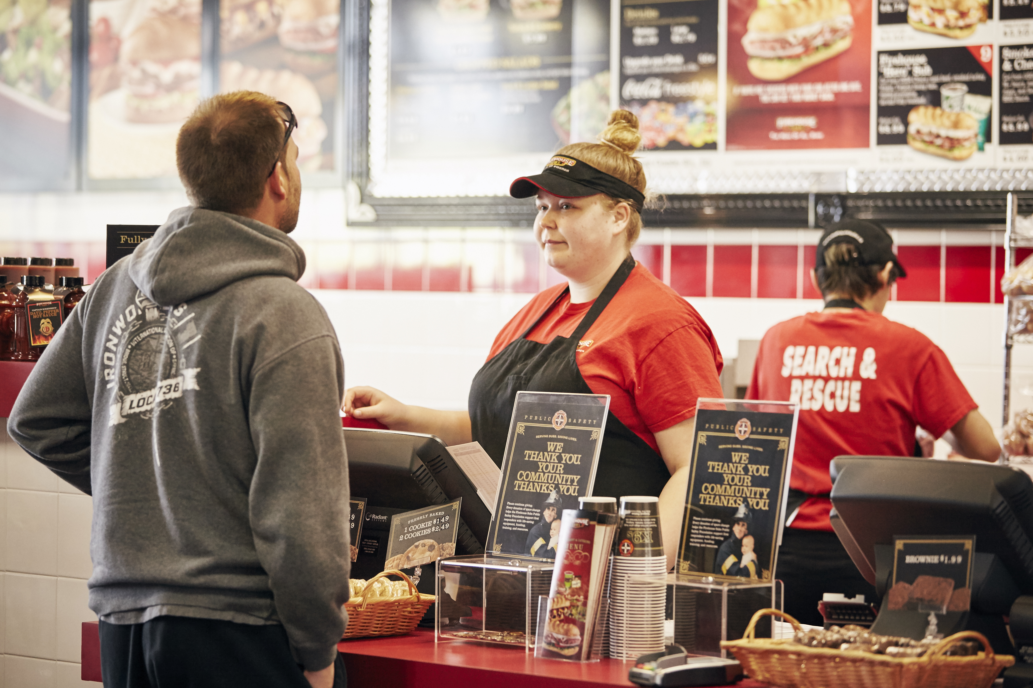 Customer ordering at the counter of Firehouse Subs restaurant