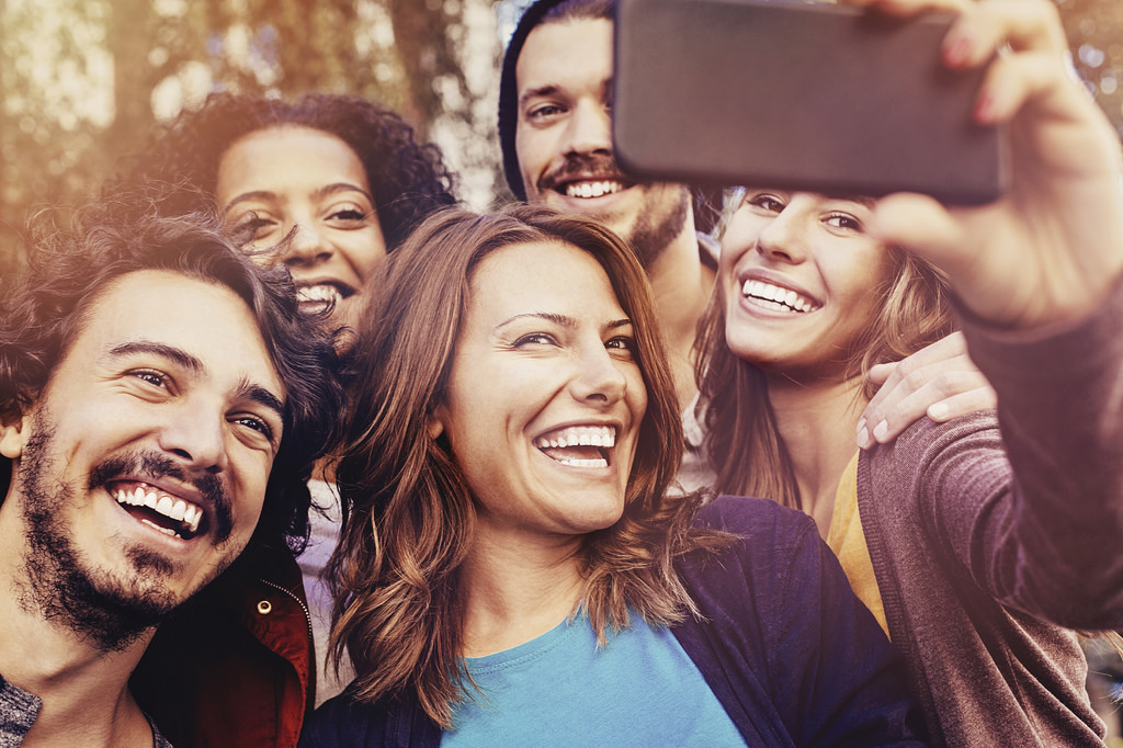 Group of men and women taking a group selfie with a phone